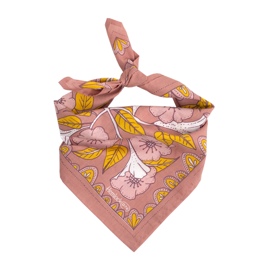 A tied bandana with floral accents. The base of the bandana is a blush color with blush, white, and yellow accents.